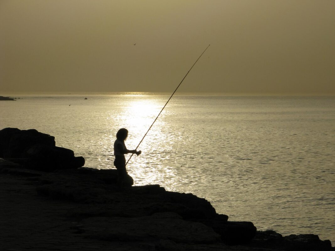 צללית דייג על מזח בת גלים